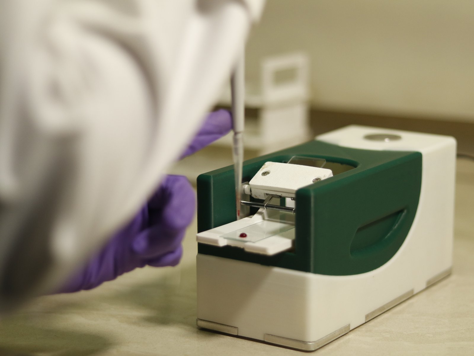 Rheoheme blood smear device in use, a gloved hand placing a blood drop on a slide