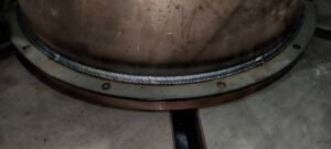 Close-up of a uniform robot weld bead on a steel vessel flange at xLogic's dark factory