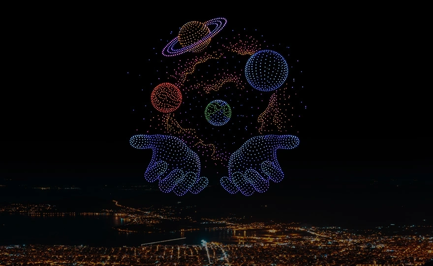 BotLab Dynamics drone swarm forming hands holding planets in the night sky