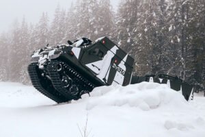 BvS10 articulated all-terrain vehicle with tracks climbing over a snow bank in a snowy forest