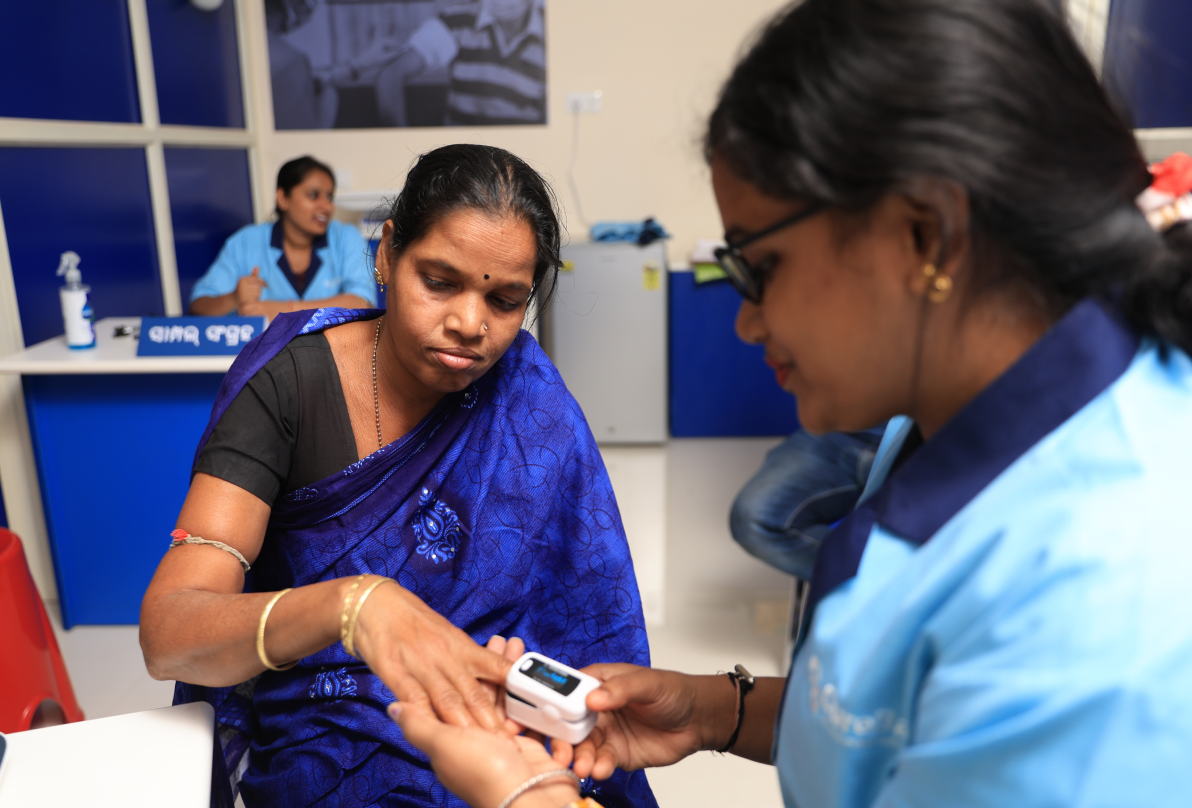 A CureBay clinic worker conducting a health screening for a patient inside a CureBay eClinic
