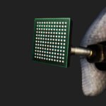 Packaged Secure IoT system-on-chip held in a gloved hand — official Mindgrove Technologies image