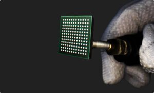 Packaged Secure IoT system-on-chip held in a gloved hand — official Mindgrove Technologies image