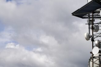 Antenna tower with microwave dishes under a cloudy sky, 1200x630 cover