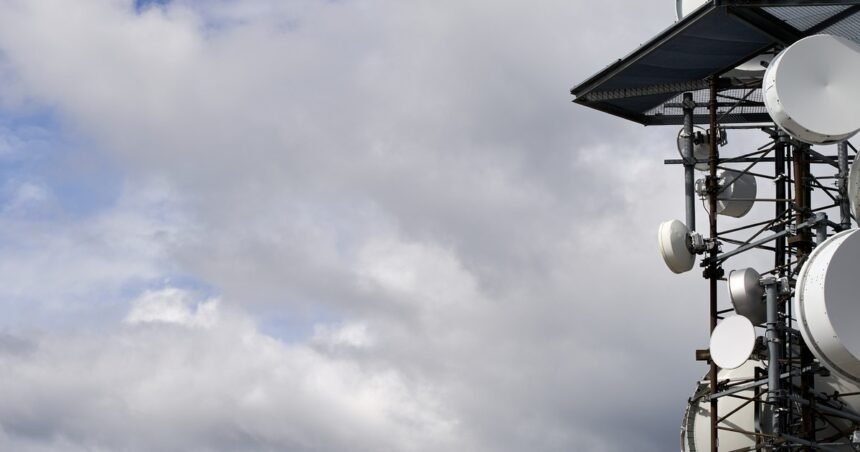 Antenna tower with microwave dishes under a cloudy sky, 1200x630 cover